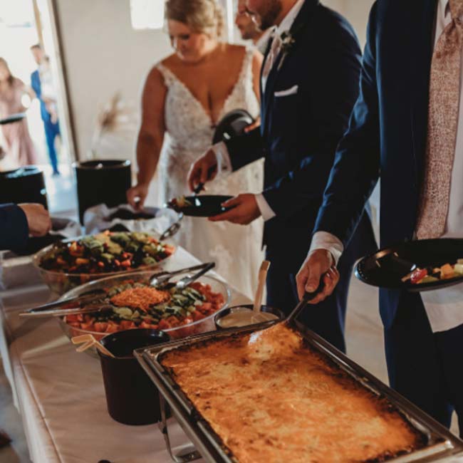 A bride and groom enjoy catering at their wedding reception in the Rustique Barn.
