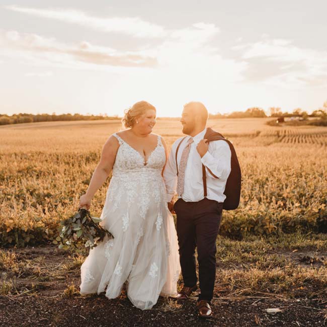 Bride and groom smiling in a sunlit Minnesota field, dressed for their wedding ceremony.