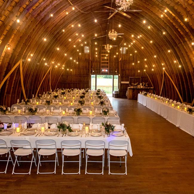 Rustique Barn wedding venue with long banquet tables set under glowing string lights.