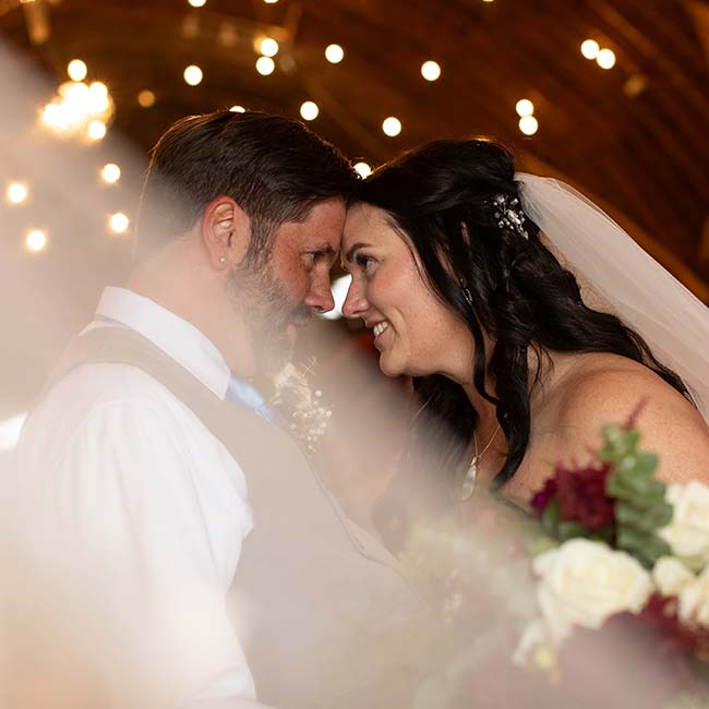 Bride and groom smile under twinkling lights at their romantic wedding ceremony.